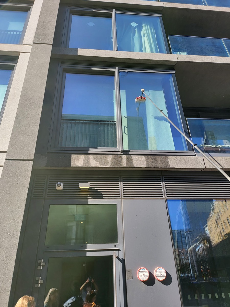 Cleaning apartment block windows with a water-fed pole in East London