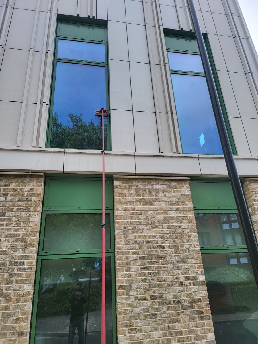 Water-fed pole cleaning tall office windows in London
